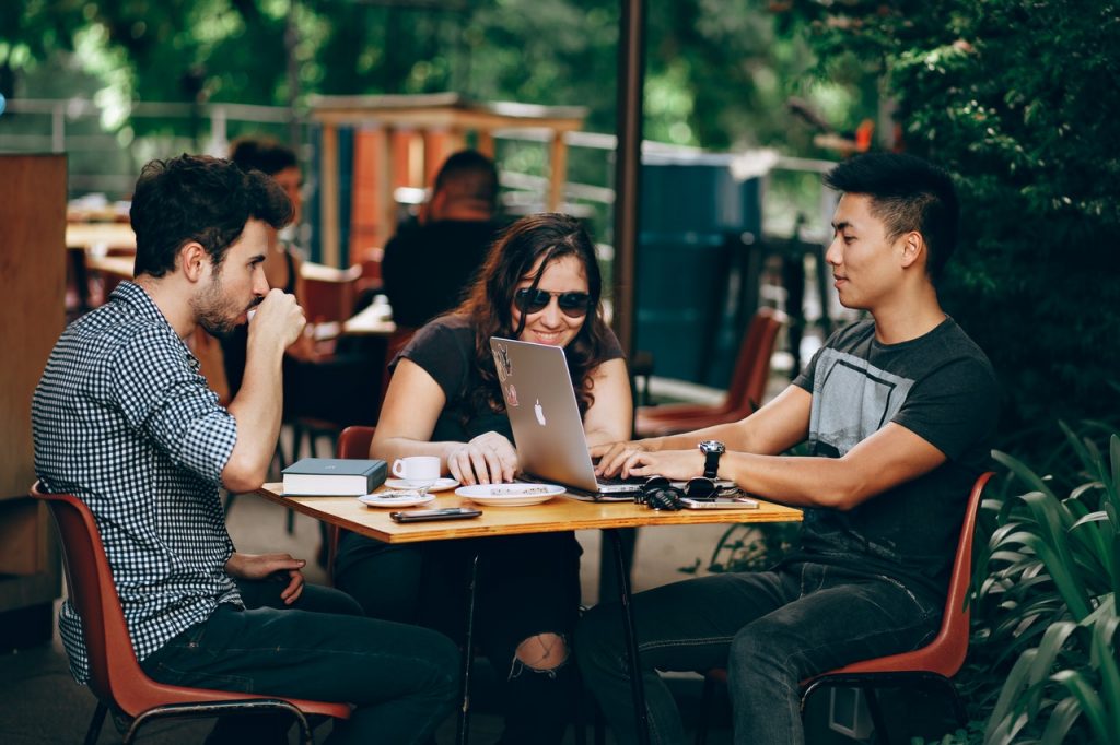 a group of people sitting at a table with laptops