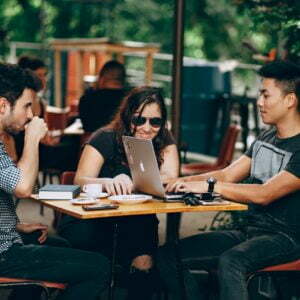 a group of people sitting at a table with laptops