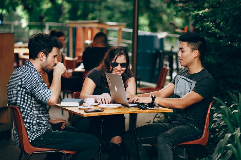 a group of people sitting at a table with laptops