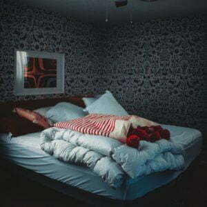 a bed with a pillow and a picture on the wall