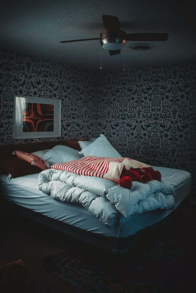a bed with a pillow and a picture on the wall