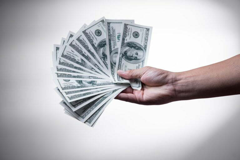 a hand holding a stack of cash