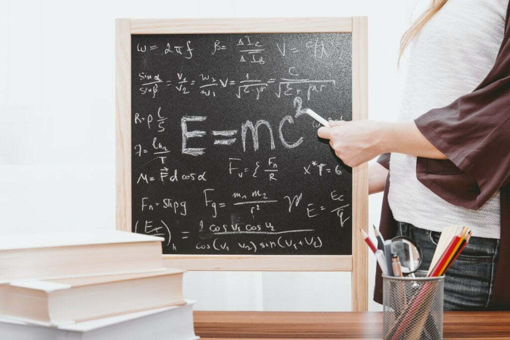 a person writing on a chalkboard