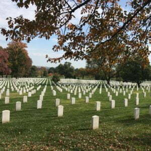 a cemetery with many headstones with Arlington National Cemetery in the background